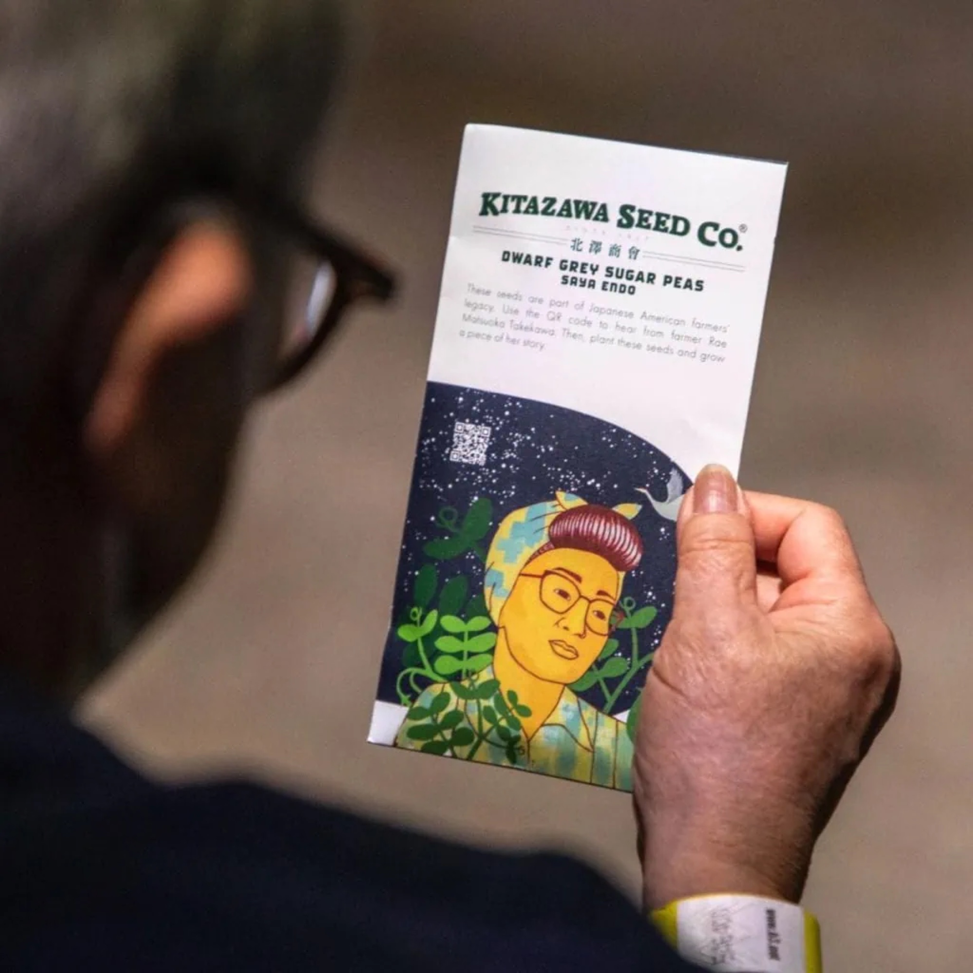 Visitor holding an Emerging Radiance seed packet with a story QR code